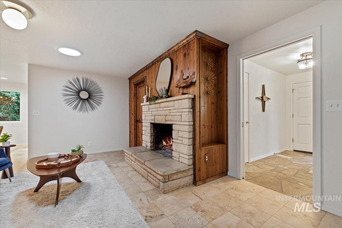 Living room with stone tile floors, a stone fireplace, and recessed lighting