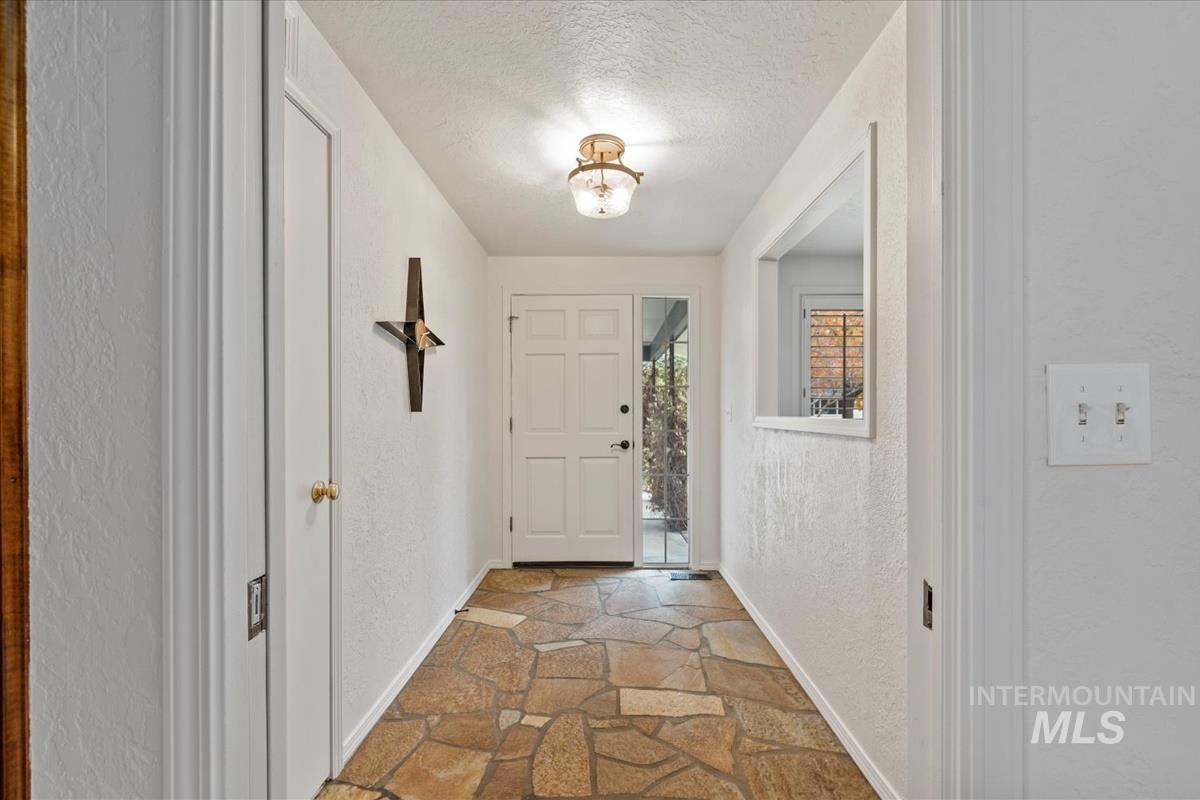 Entryway featuring a textured wall, a textured ceiling, and light stone finish floors