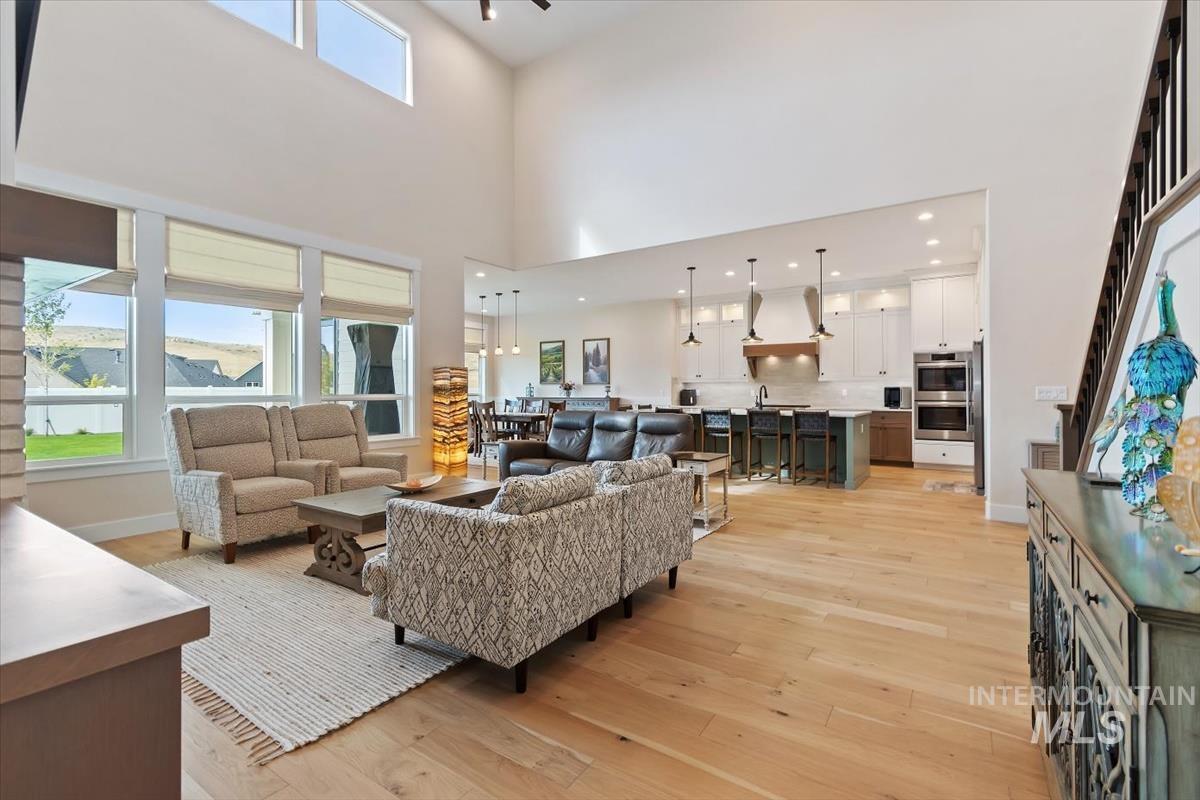 Living room with light wood-type flooring, recessed lighting, and a towering ceiling