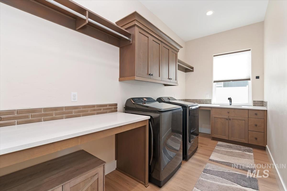 Laundry area with washer and dryer, light wood-style floors, recessed lighting, and cabinet space
