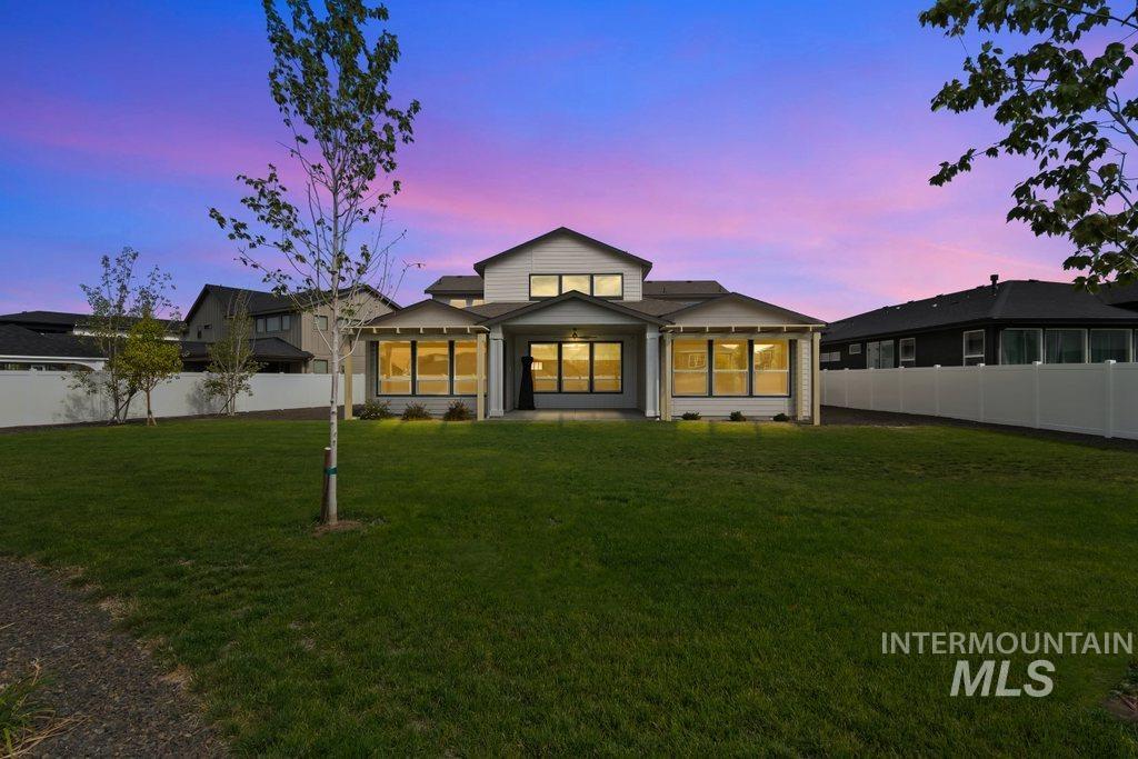 Back of property at dusk with a patio area and a fenced backyard