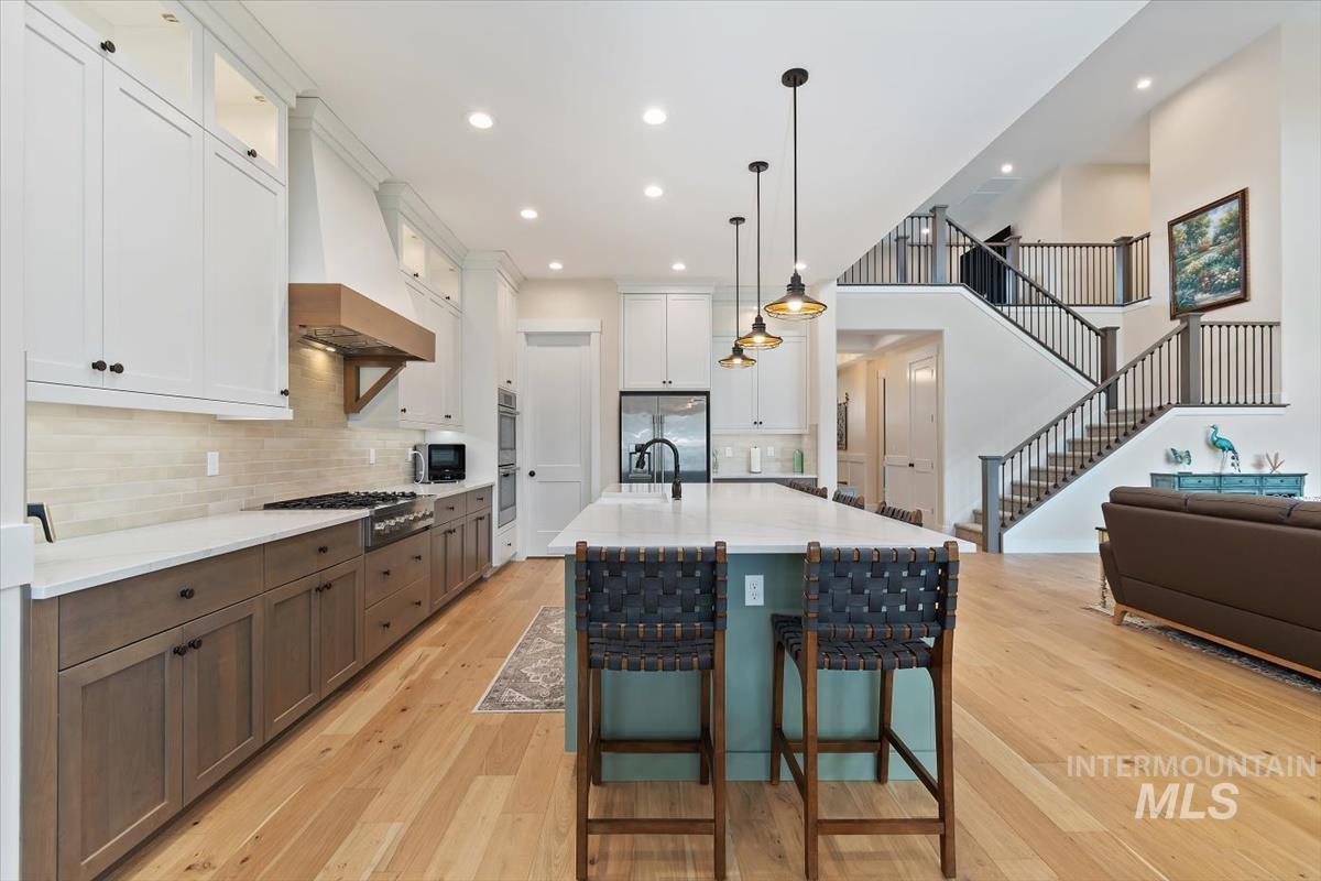 Kitchen with decorative light fixtures, a kitchen bar, white cabinetry, a center island with sink, and tasteful backsplash