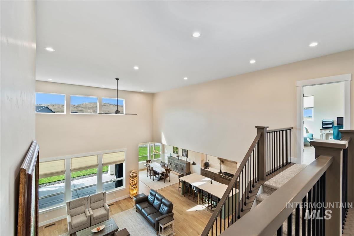 Living area with light wood-type flooring, recessed lighting, healthy amount of natural light, and a towering ceiling