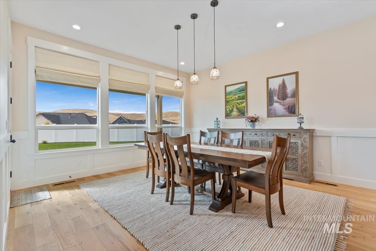 Dining area featuring light wood-style flooring, a decorative wall, wainscoting, and recessed lighting