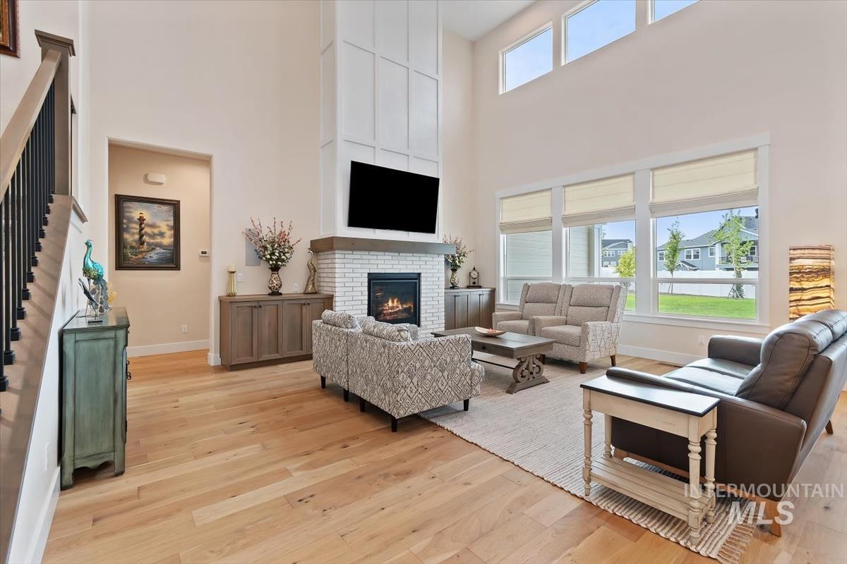 Living area with light wood-style floors, a fireplace, a towering ceiling, and stairway