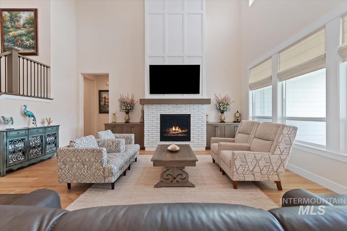 Living area with wood finished floors, a fireplace, and a high ceiling