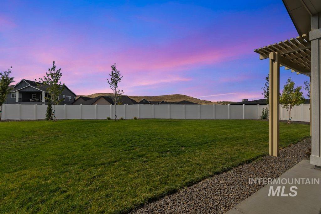 Yard at dusk with a fenced backyard and a pergola