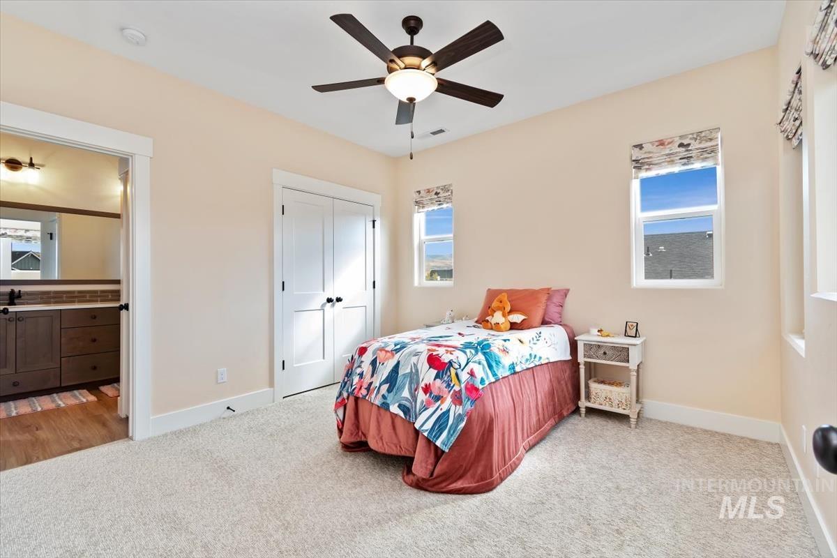 Carpeted bedroom featuring ceiling fan and a closet