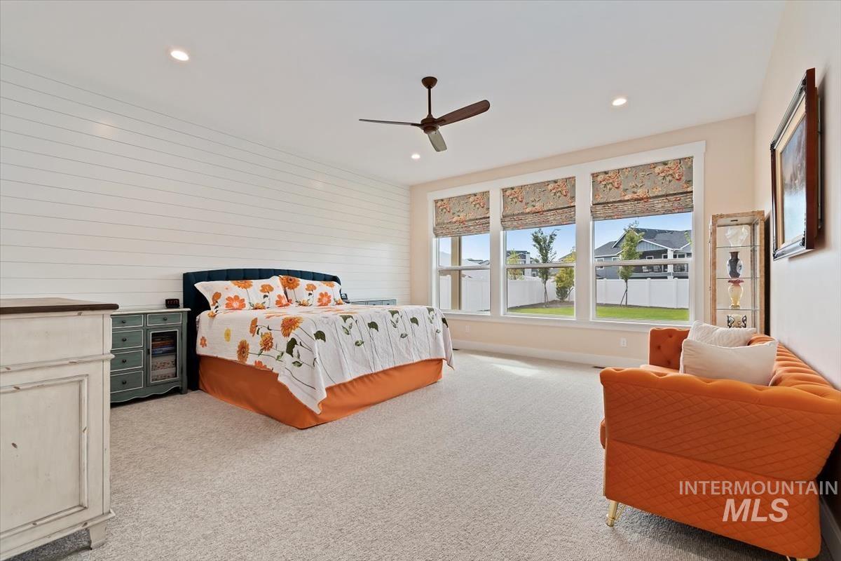 Bedroom featuring light carpet, ceiling fan, recessed lighting, and wood walls