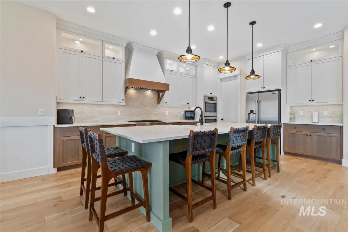 Kitchen with glass insert cabinets, decorative backsplash, a kitchen bar, white cabinets, and recessed lighting