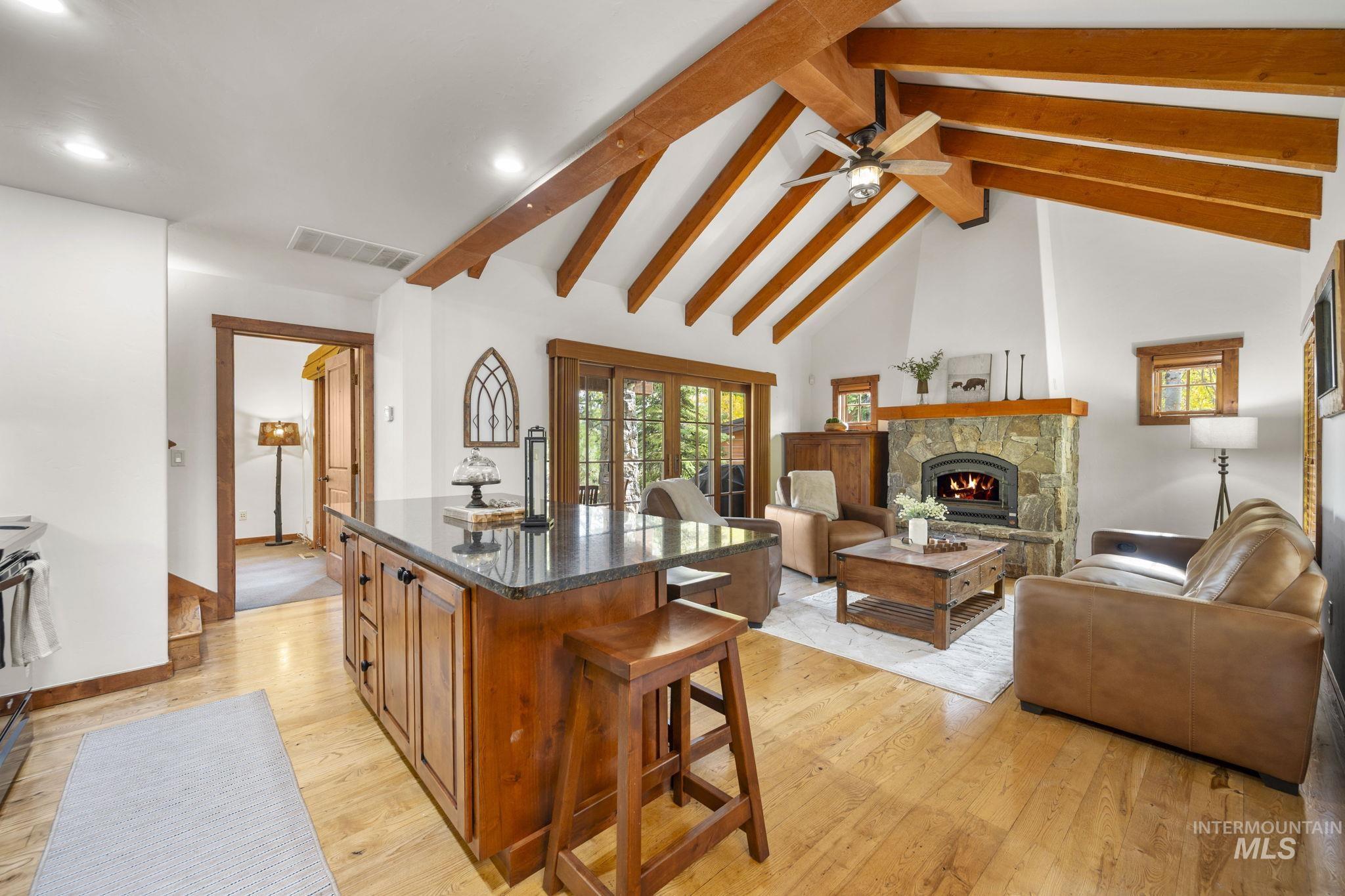 Kitchen with brown cabinets, dark stone counters, beamed ceiling, a breakfast bar, and a fireplace