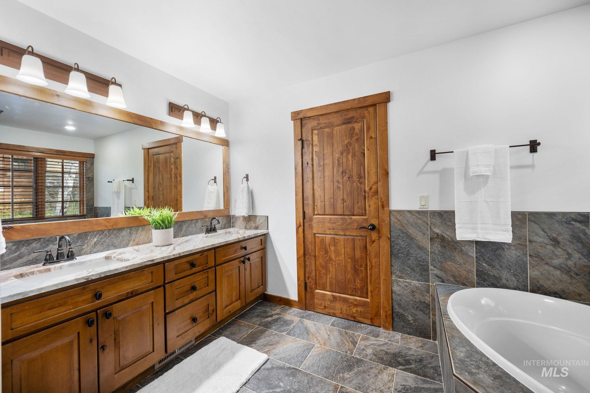 Full bath featuring double vanity and tiled tub