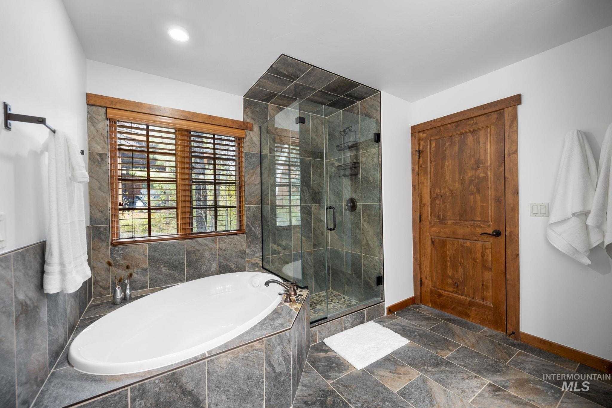 Full bathroom with a bath, stone tile flooring, and a stall shower