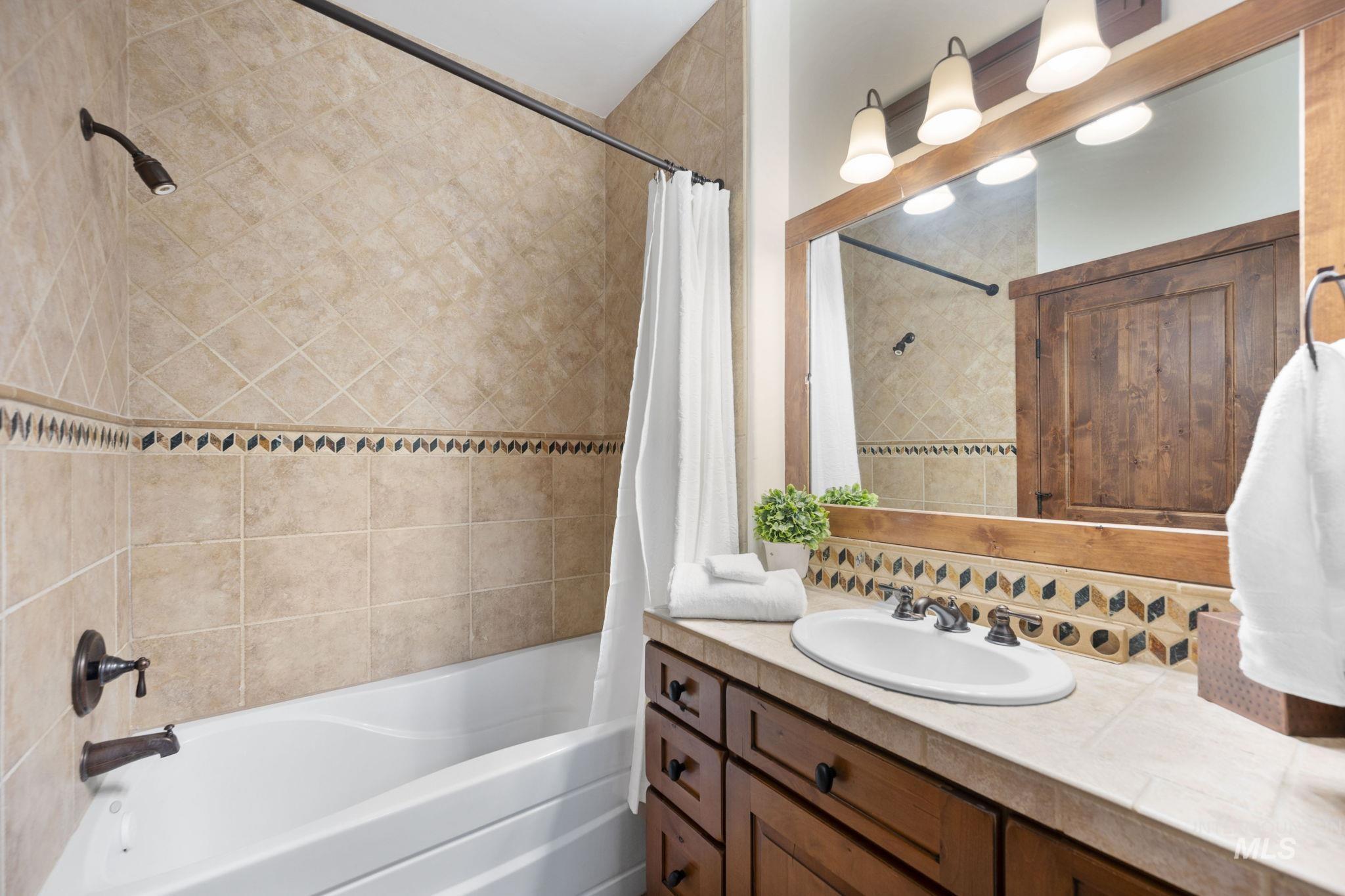 Full bath with shower / tub combo, vanity, and tasteful backsplash