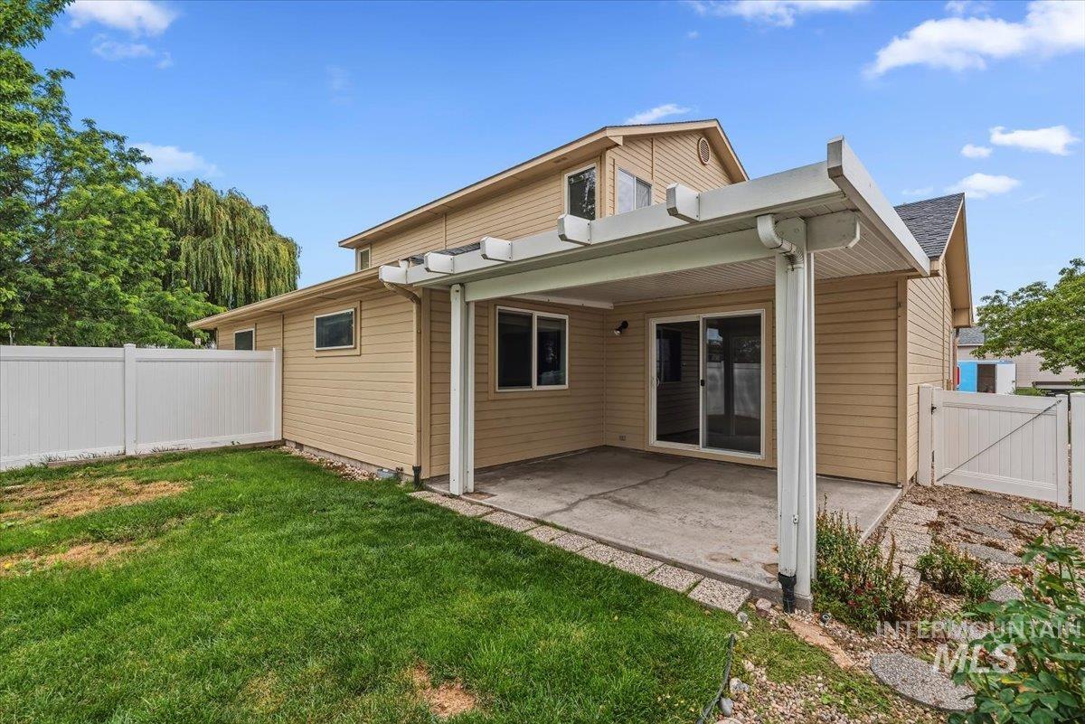 Rear exterior featuring a covered patio with concrete flooring, sliding glass door access, and a manicured lawn area
