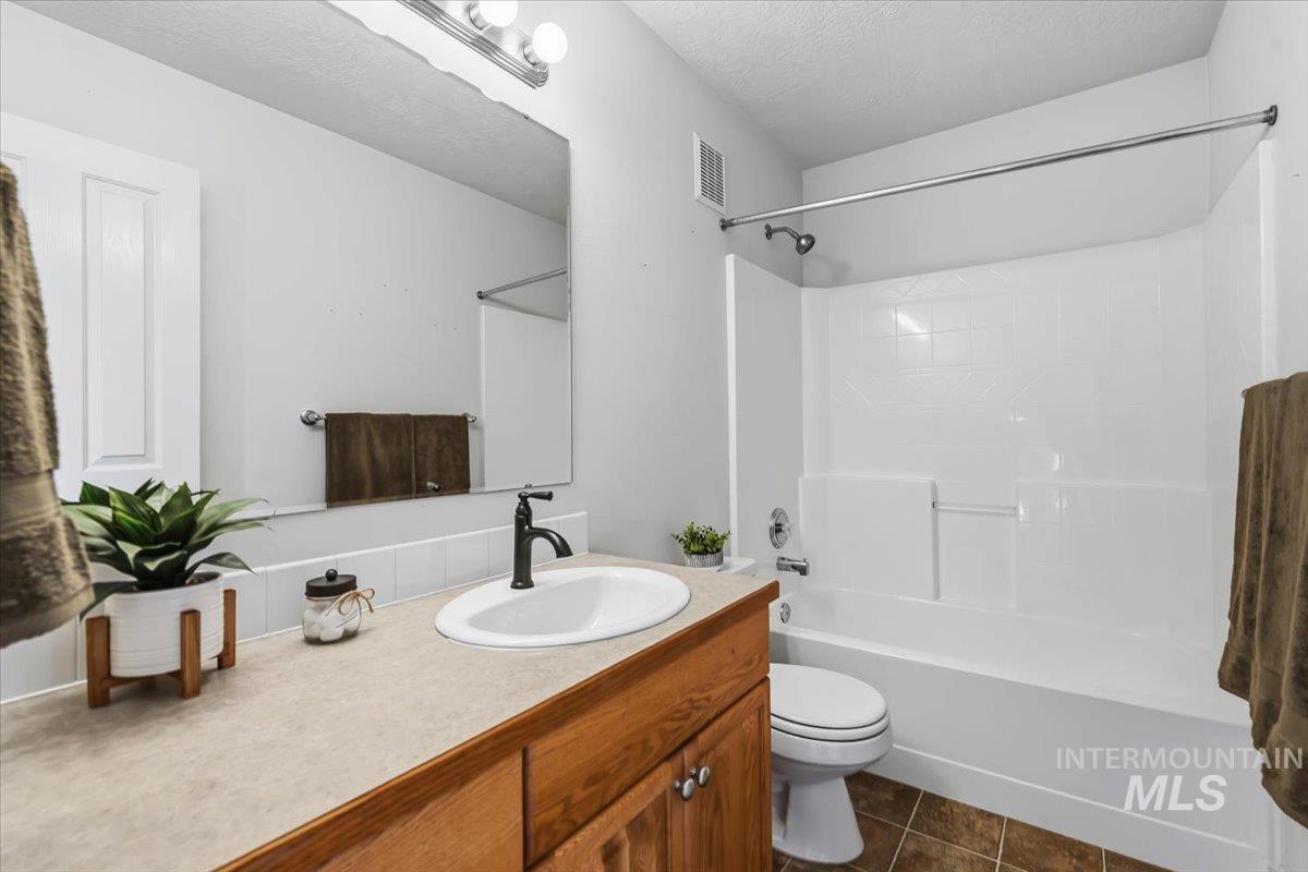 Bathroom featuring a wood-finish vanity with a light-toned countertop and an integrated sink