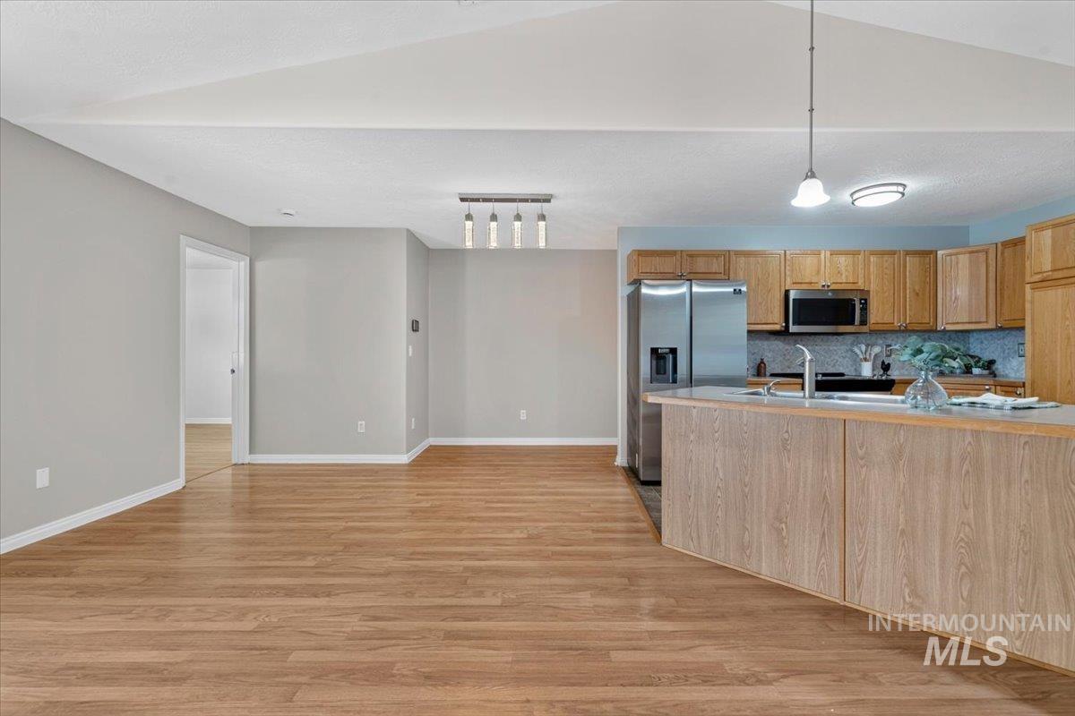 Open-concept living space featuring wood-finish flooring, vaulted ceiling, and light gray walls