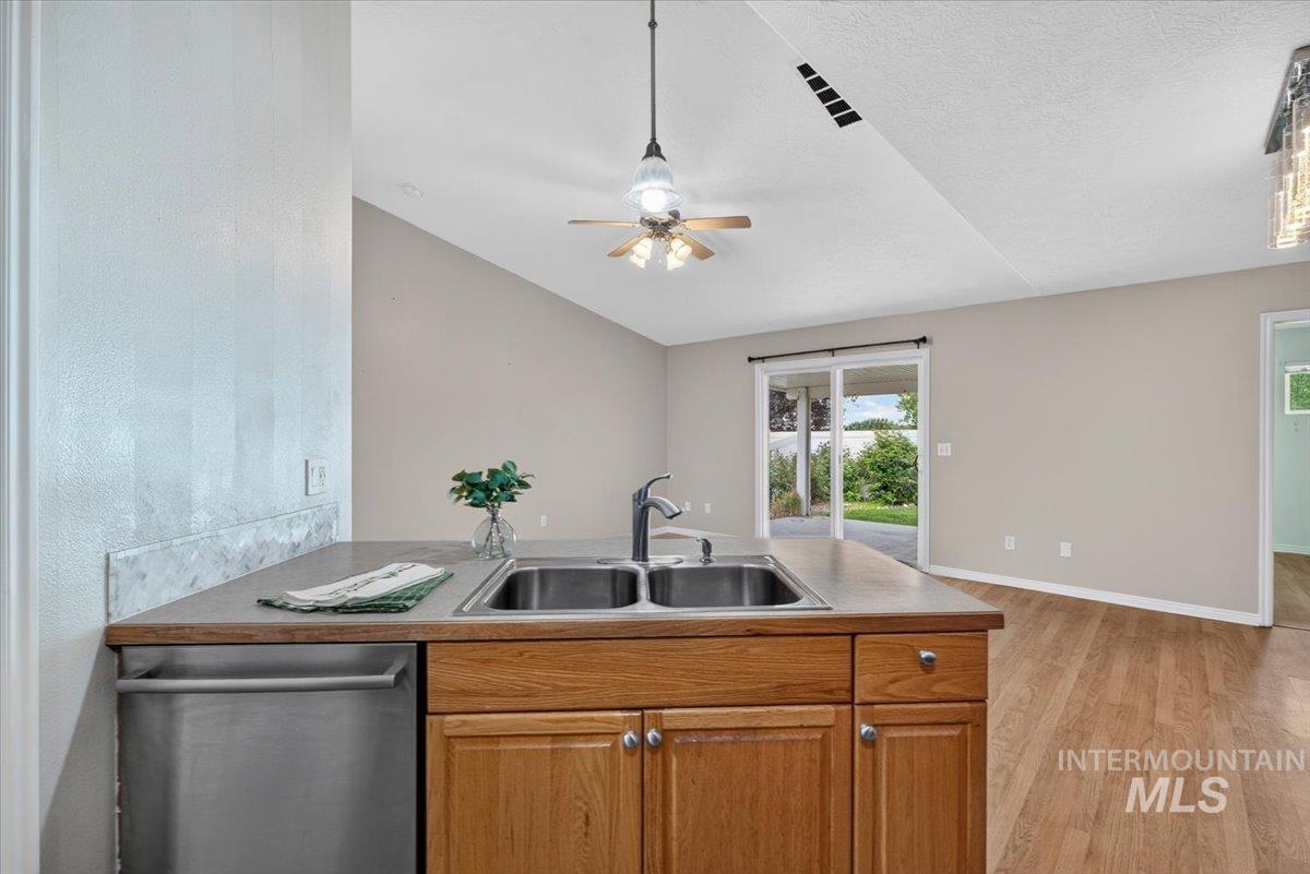 Kitchen island featuring a double basin stainless steel sink, a stainless steel dishwasher, and natural wood cabinetry