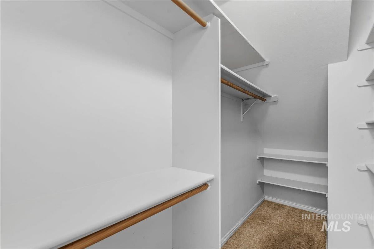 Walk-in closet featuring built-in shelving, hanging rods, and light-toned carpet flooring