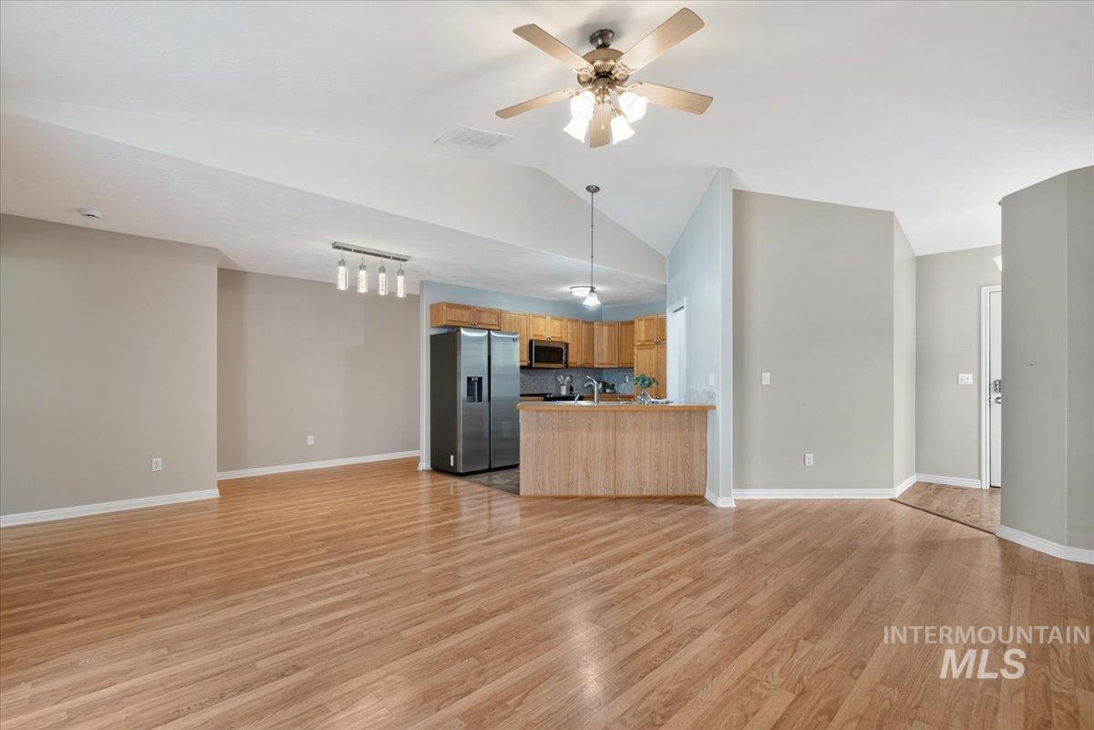Open-concept living space featuring wood-finish flooring, vaulted ceilings, and neutral wall tones