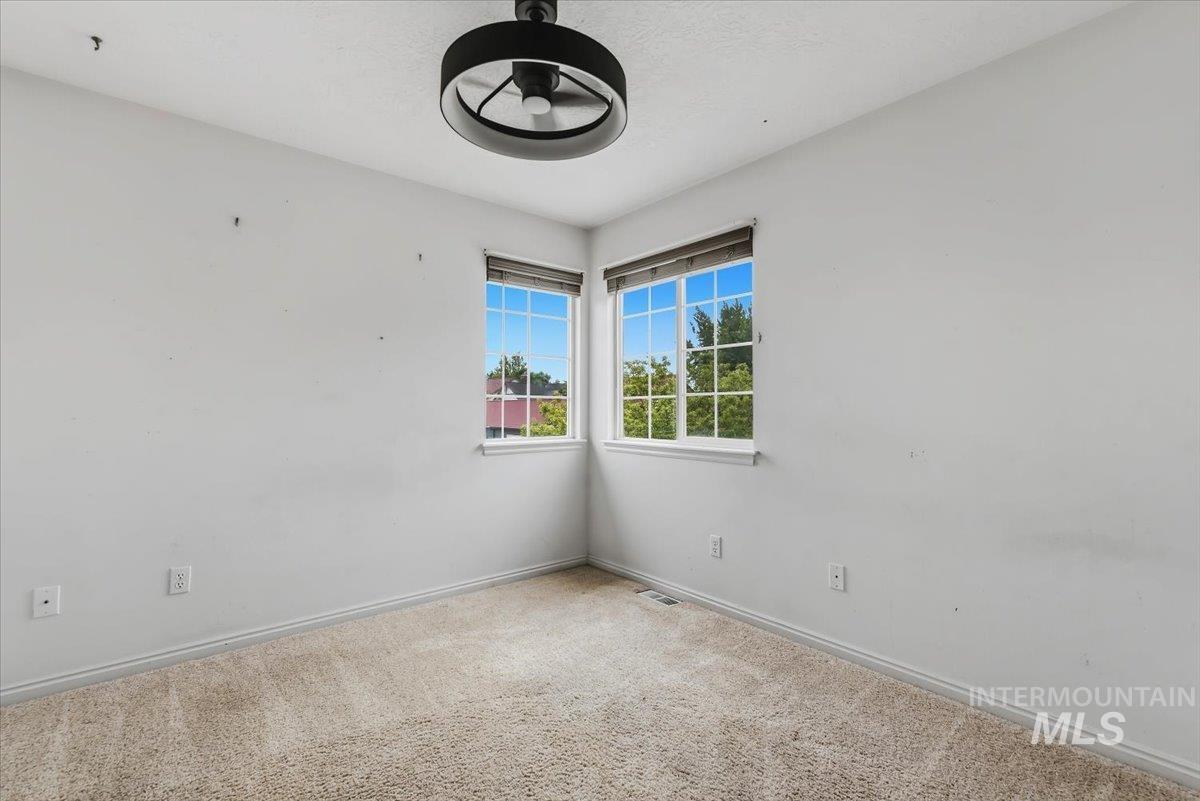 Room featuring carpet flooring, white walls, two windows with white grilles, and a flush-mount ceiling light fixture