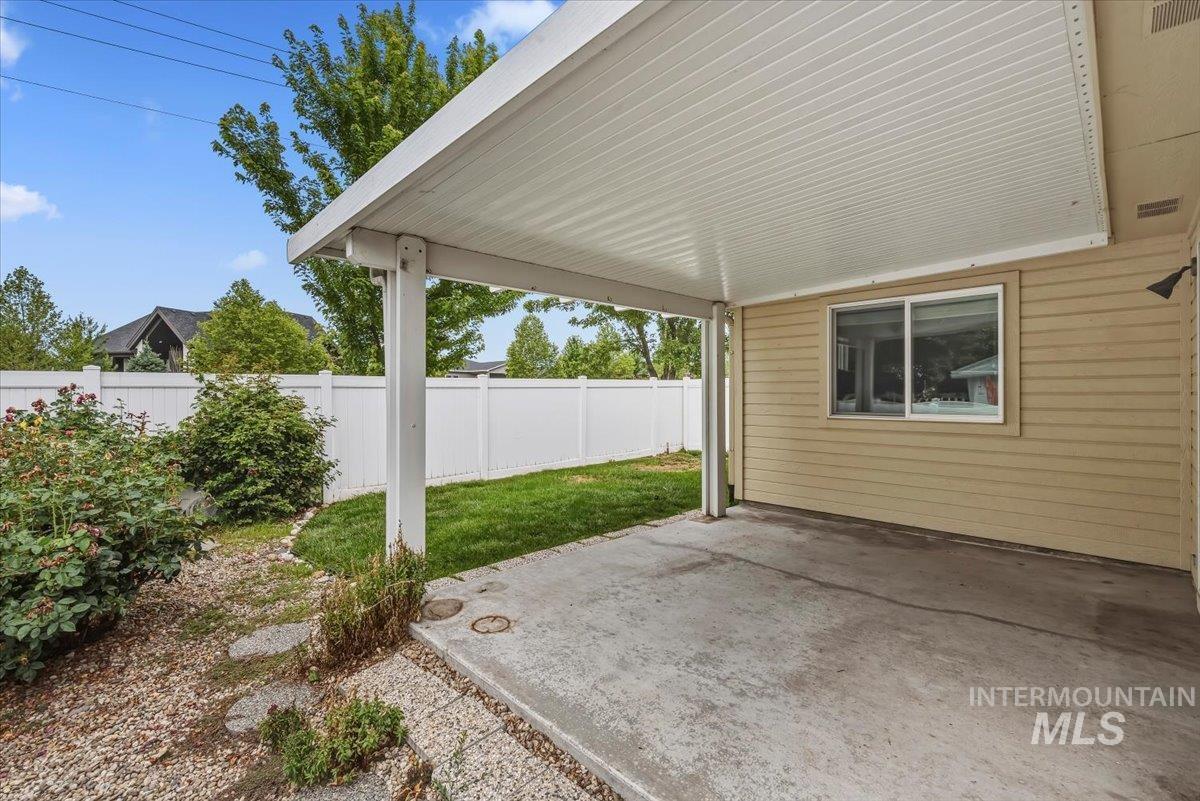 Covered concrete patio with a paneled ceiling, beige horizontal siding, and an exterior wall light