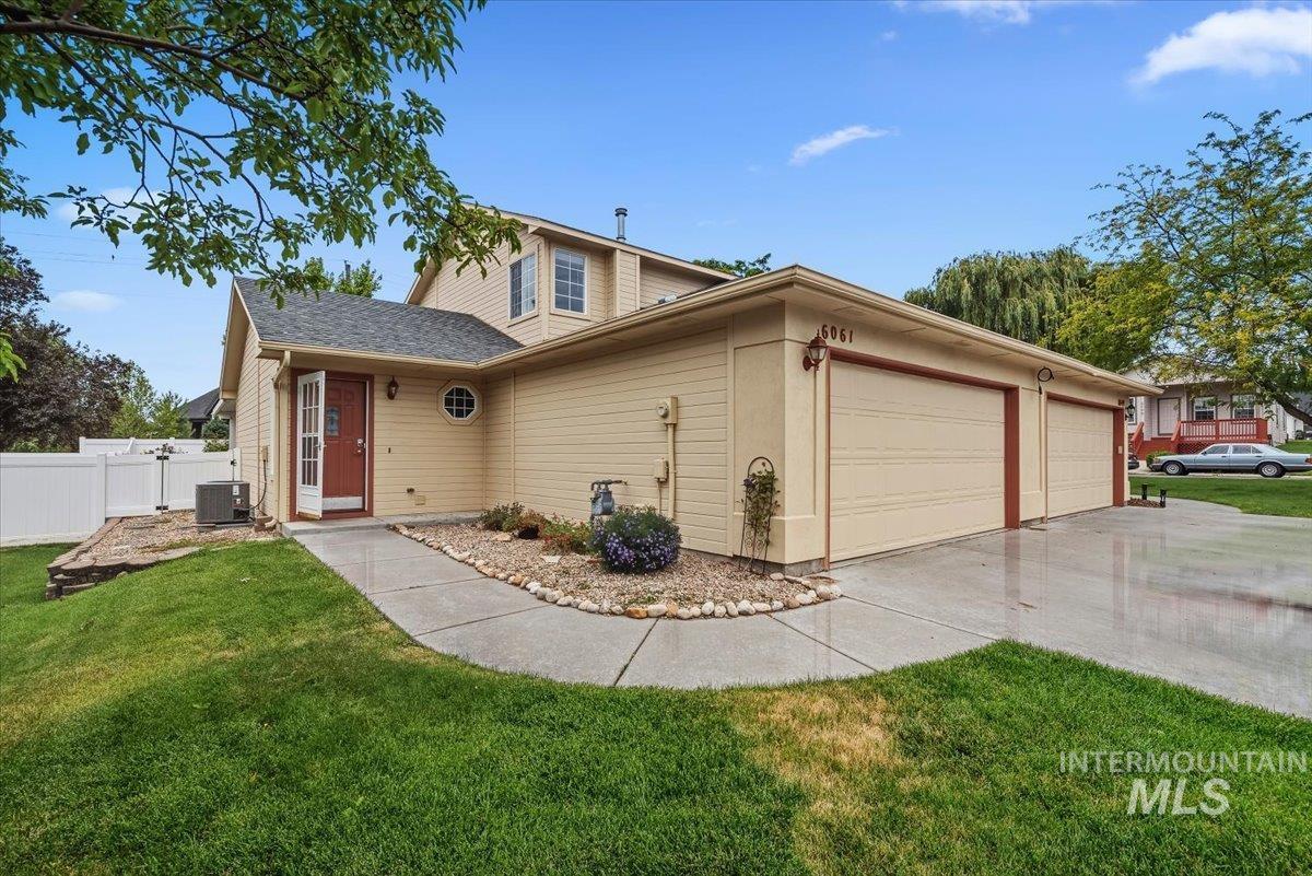 Exterior featuring a two-car garage, concrete driveway, and a red entry door with a storm door