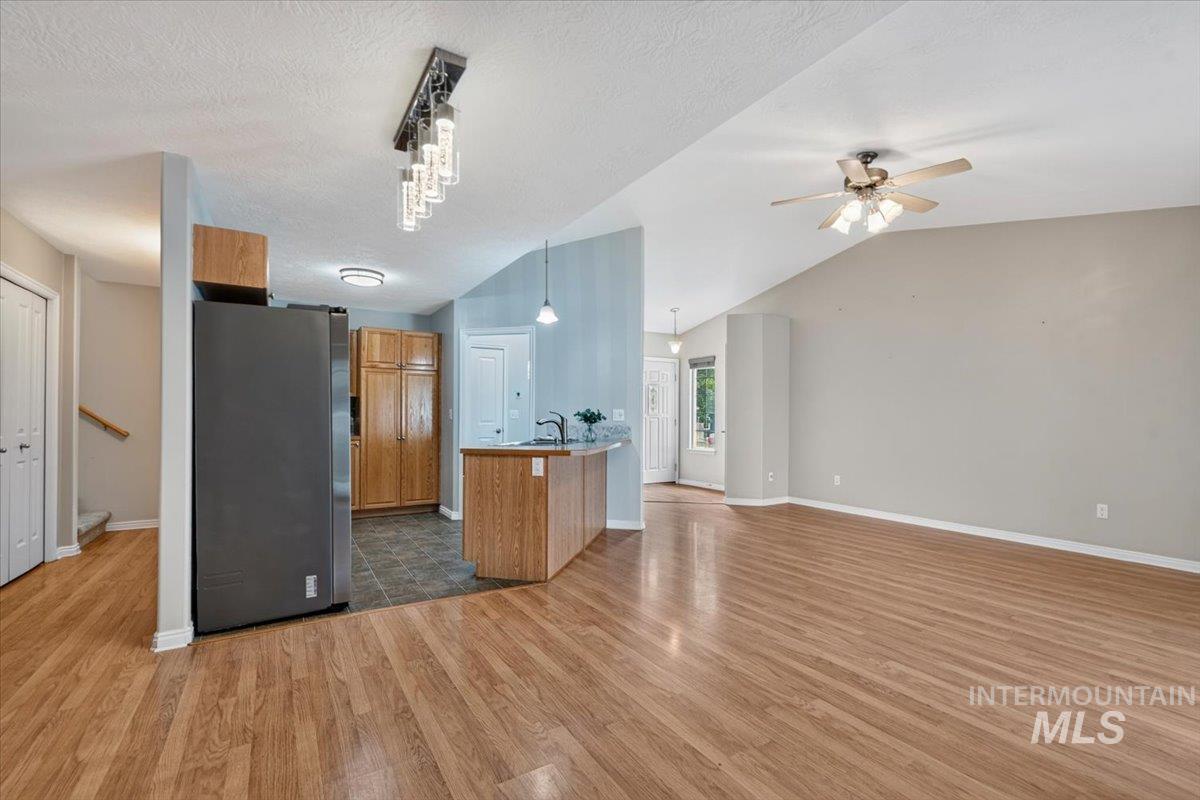 Open-concept living space featuring wood-finish flooring, vaulted ceilings, and a ceiling fan