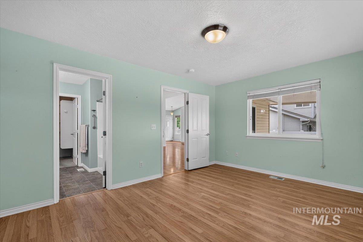 Room featuring wood-finish flooring, light green walls, a white trim package, and a double-pane window with white blinds