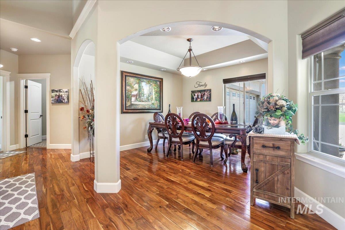 Dining area with arched walkways, wood finished floors, healthy amount of natural light, recessed lighting, and ornamental molding