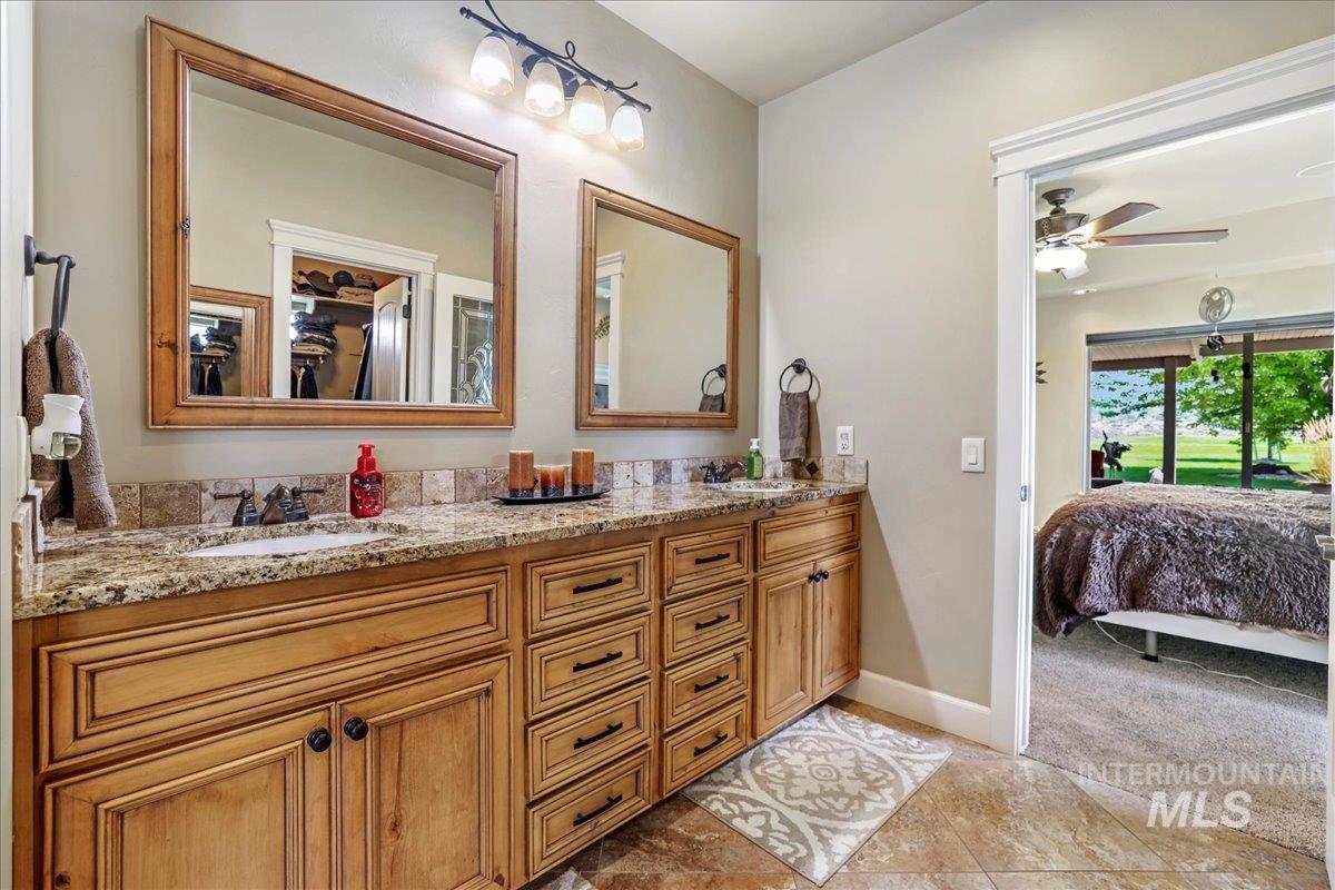 Bathroom with ensuite bath, double vanity, and a ceiling fan