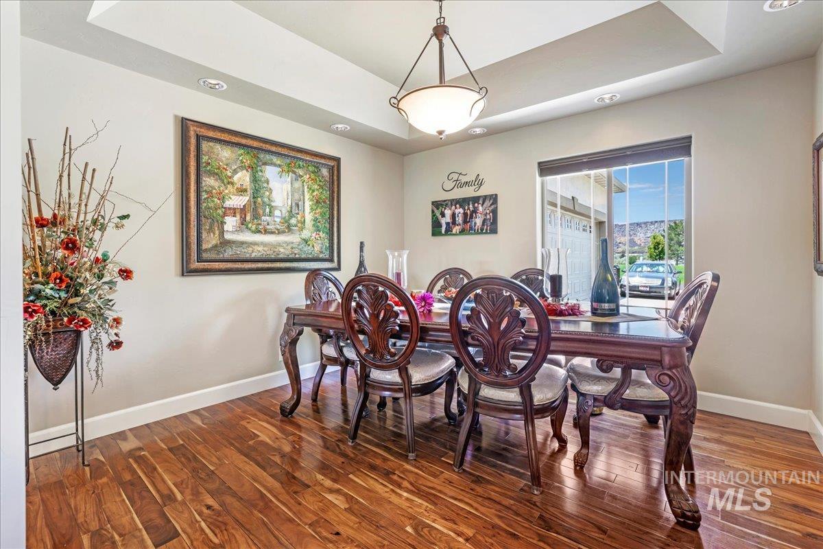 Dining space with wood finished floors, a raised ceiling, and recessed lighting