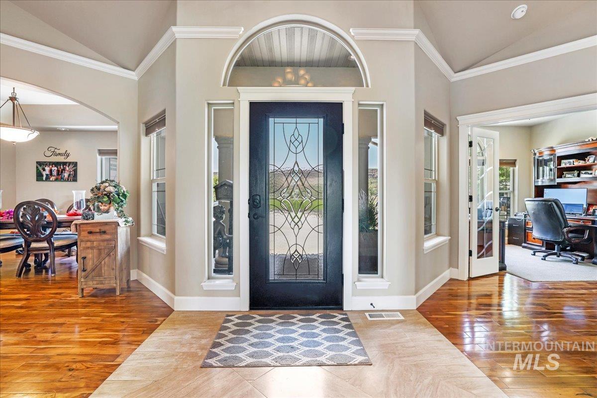 Foyer entrance with lofted ceiling, hardwood / wood-style floors, french doors, ornamental molding, and arched walkways