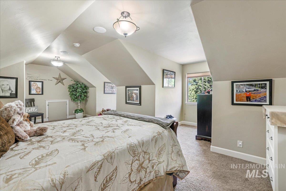 Bedroom featuring light carpet and lofted ceiling