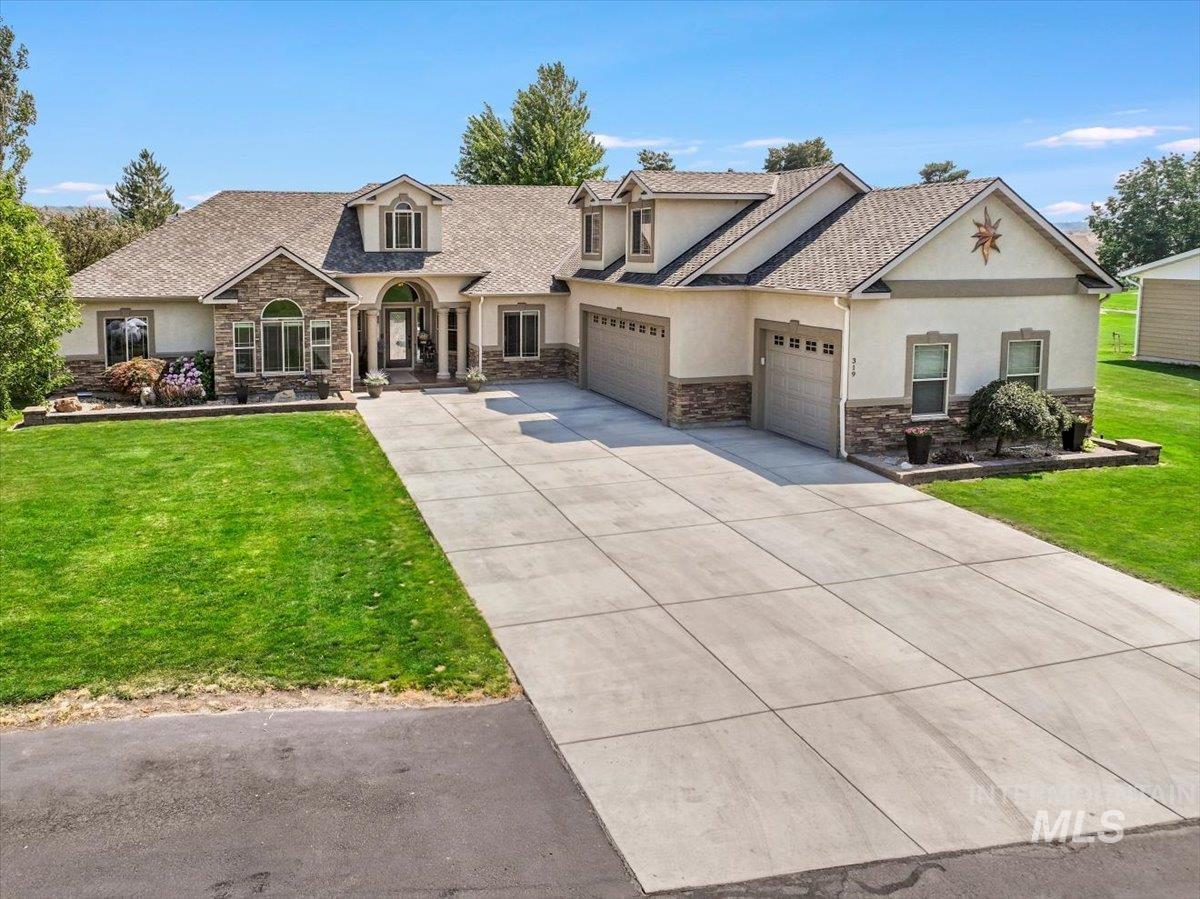 View of front of home featuring stone siding, stucco siding, a garage, and a front yard
