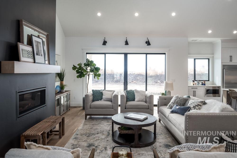 Living room with a glass covered fireplace, recessed lighting, and wood finished floors