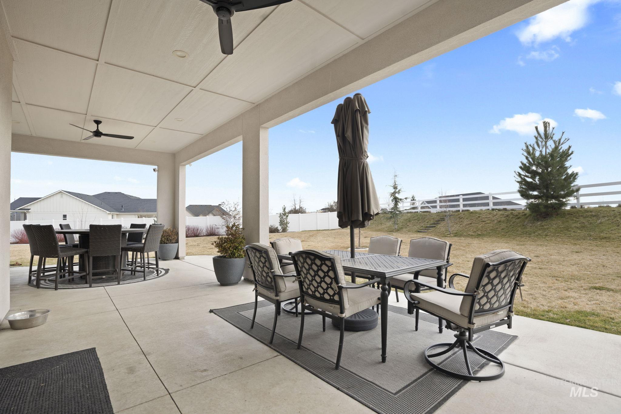 Fenced backyard featuring outdoor dining space, ceiling fan, and a patio area