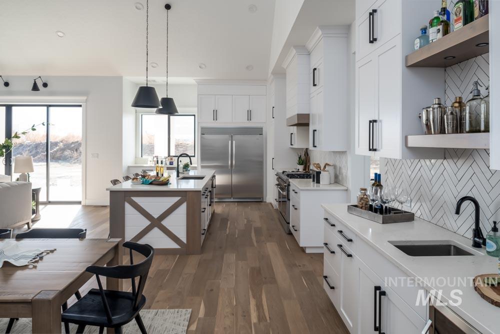 Kitchen featuring open shelves, white cabinets, high quality appliances, pendant lighting, and backsplash