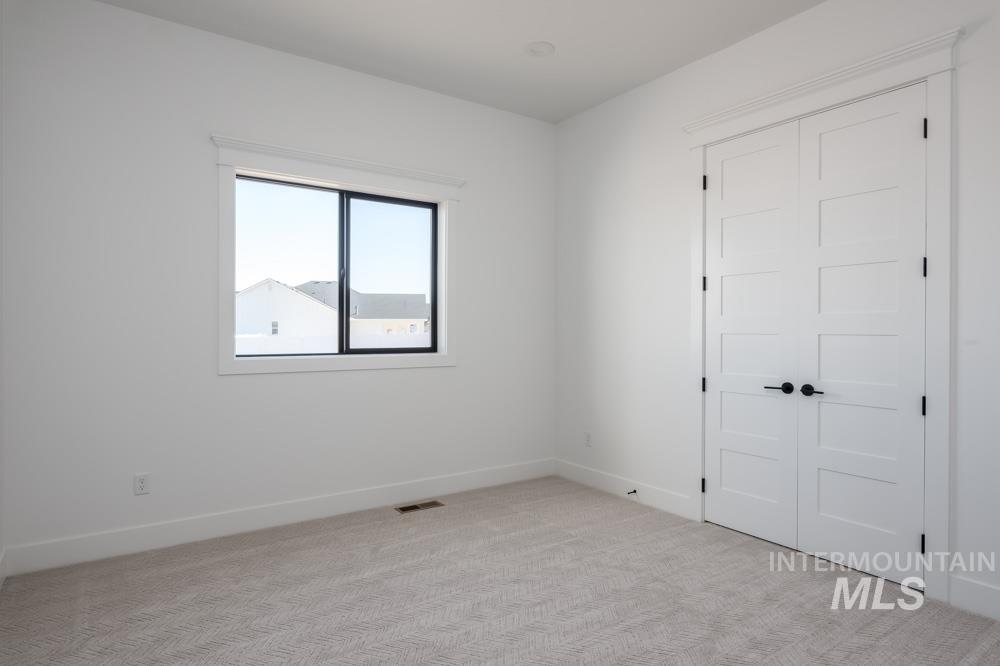 Unfurnished room featuring light carpet and baseboards