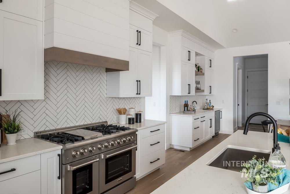 Kitchen featuring double oven range, white cabinets, open shelves, dark wood-style flooring, and tasteful backsplash