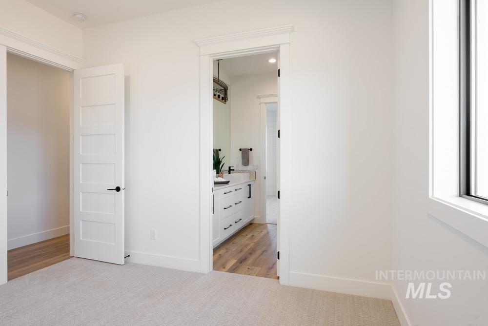 Unfurnished bedroom with light carpet and ensuite bathroom