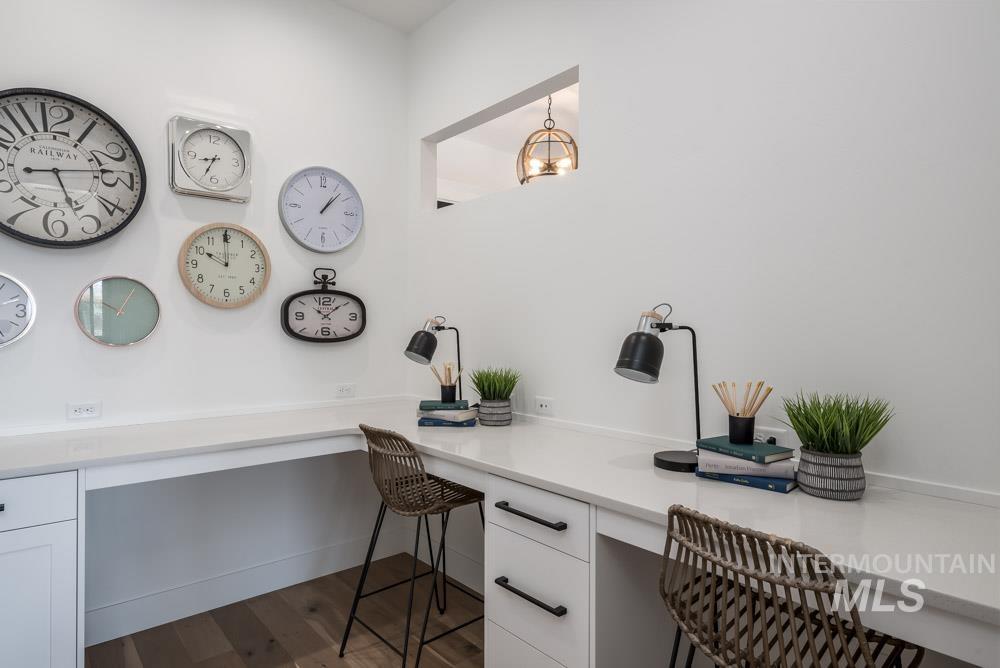 Home office featuring built in desk, dark wood-style floors, and hanging lights