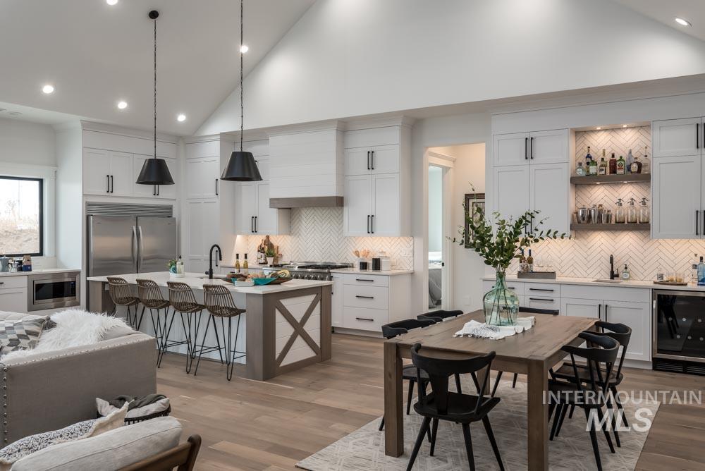 Dining area with vaulted ceiling, recessed lighting, light wood finished floors, and bar area