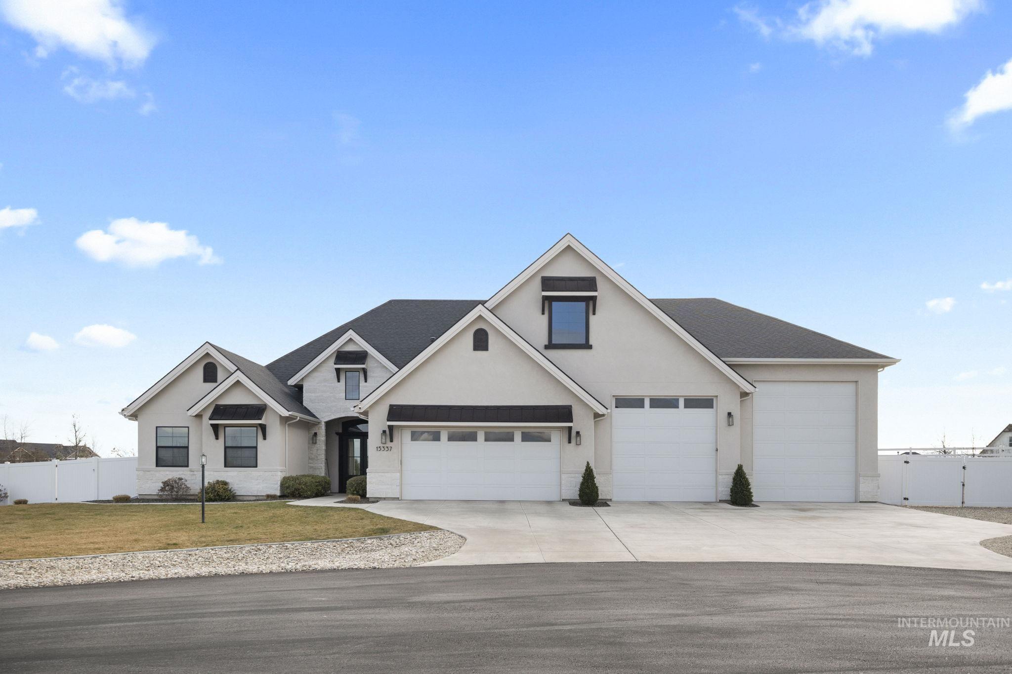 View of front of home featuring driveway, stucco siding, a gate, and an attached garage