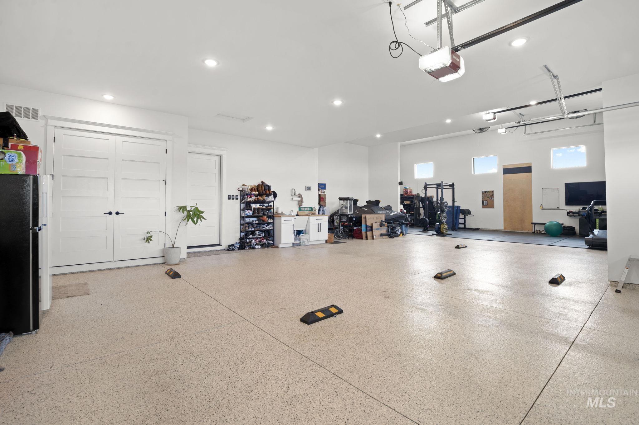 Garage with freestanding refrigerator, a garage door opener, and recessed lighting