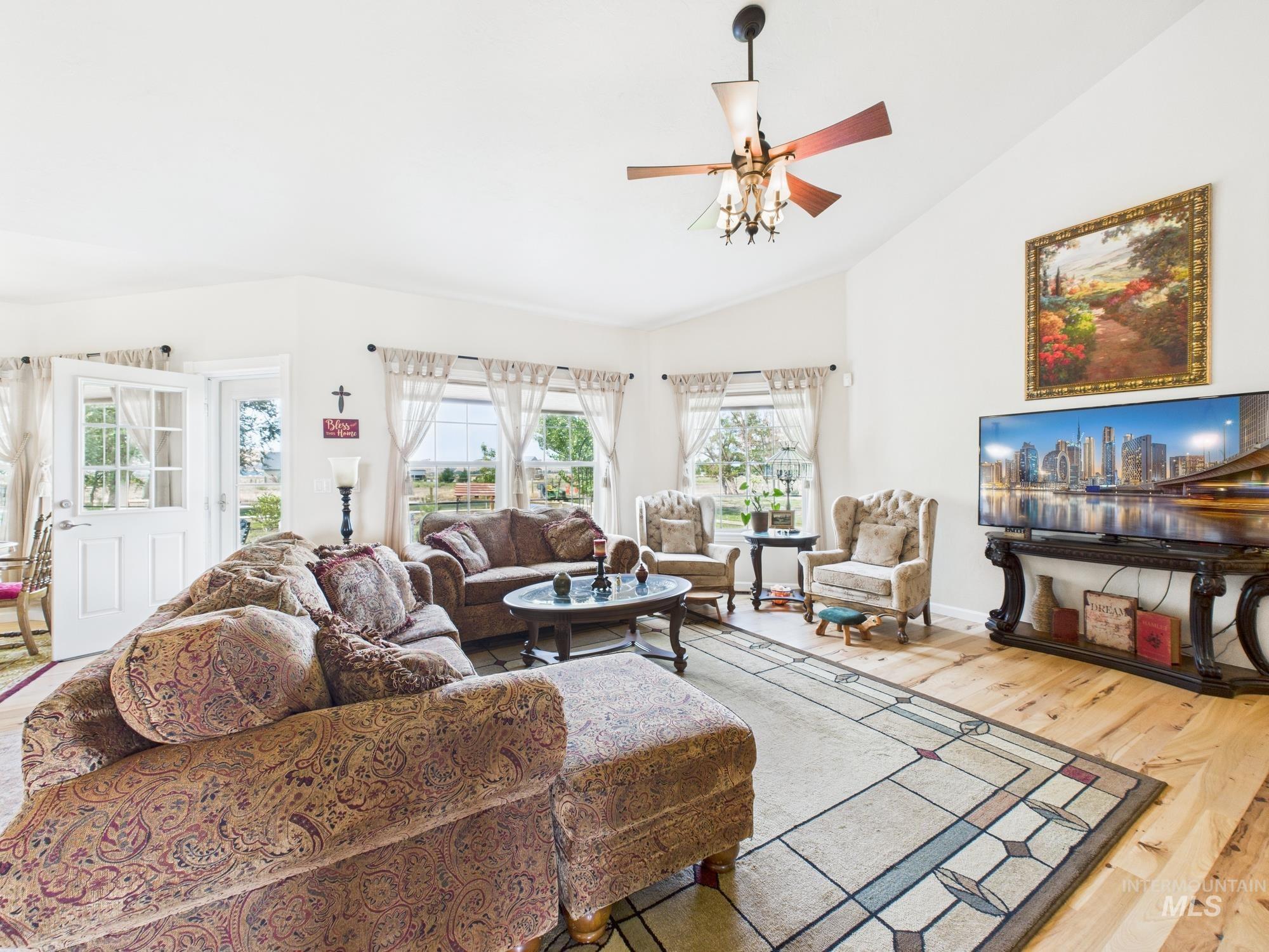 Living room with wood finished floors, a ceiling fan, and high vaulted ceiling