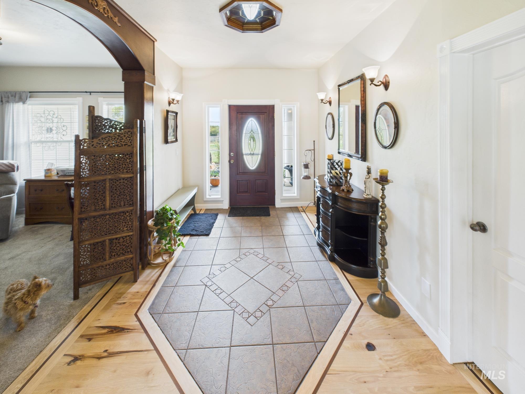 Entrance foyer with inlaid floor details, plenty of natural light, light wood-style flooring, and arched walkways