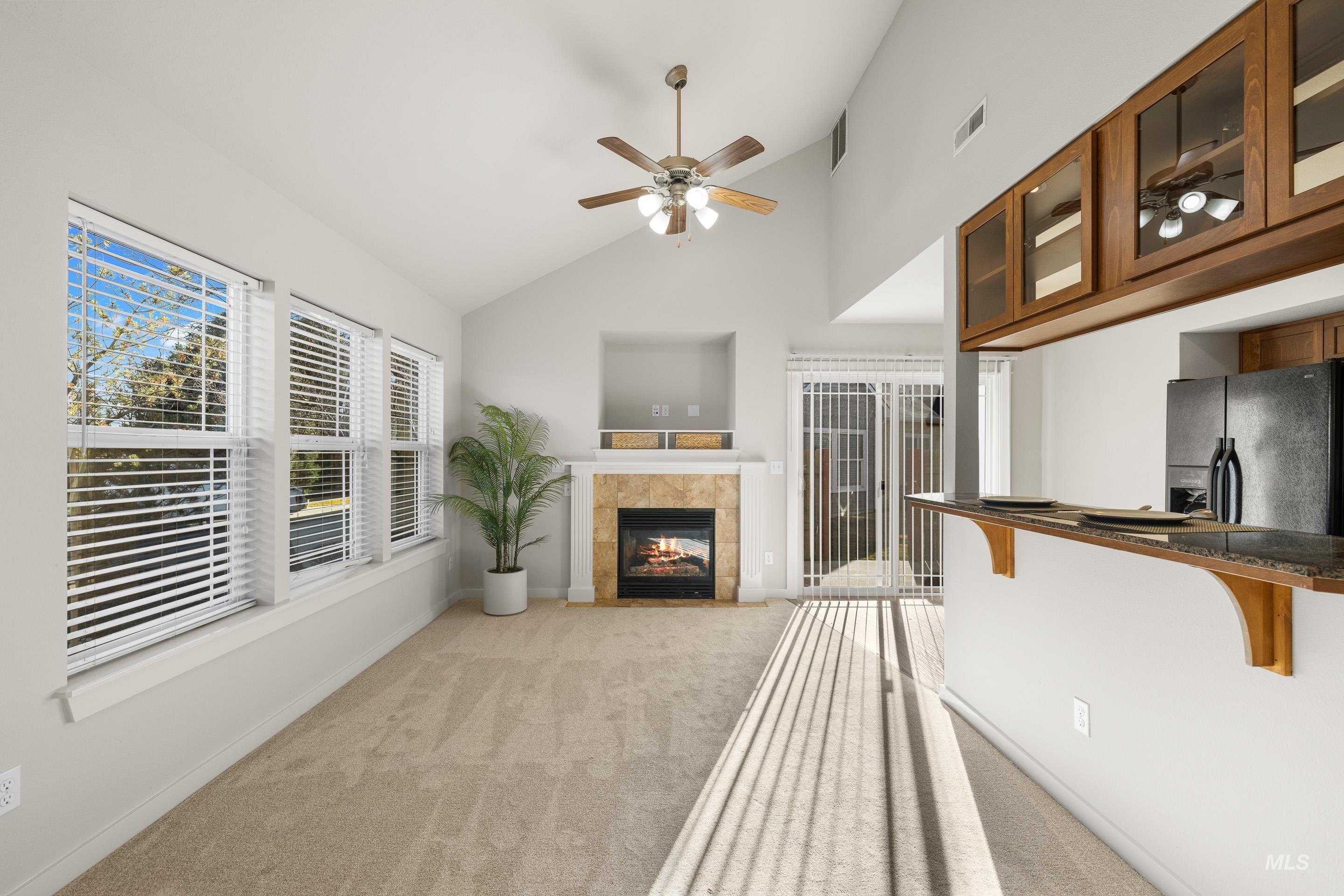 Unfurnished living room featuring lofted ceiling, light colored carpet, ceiling fan, and a fireplace