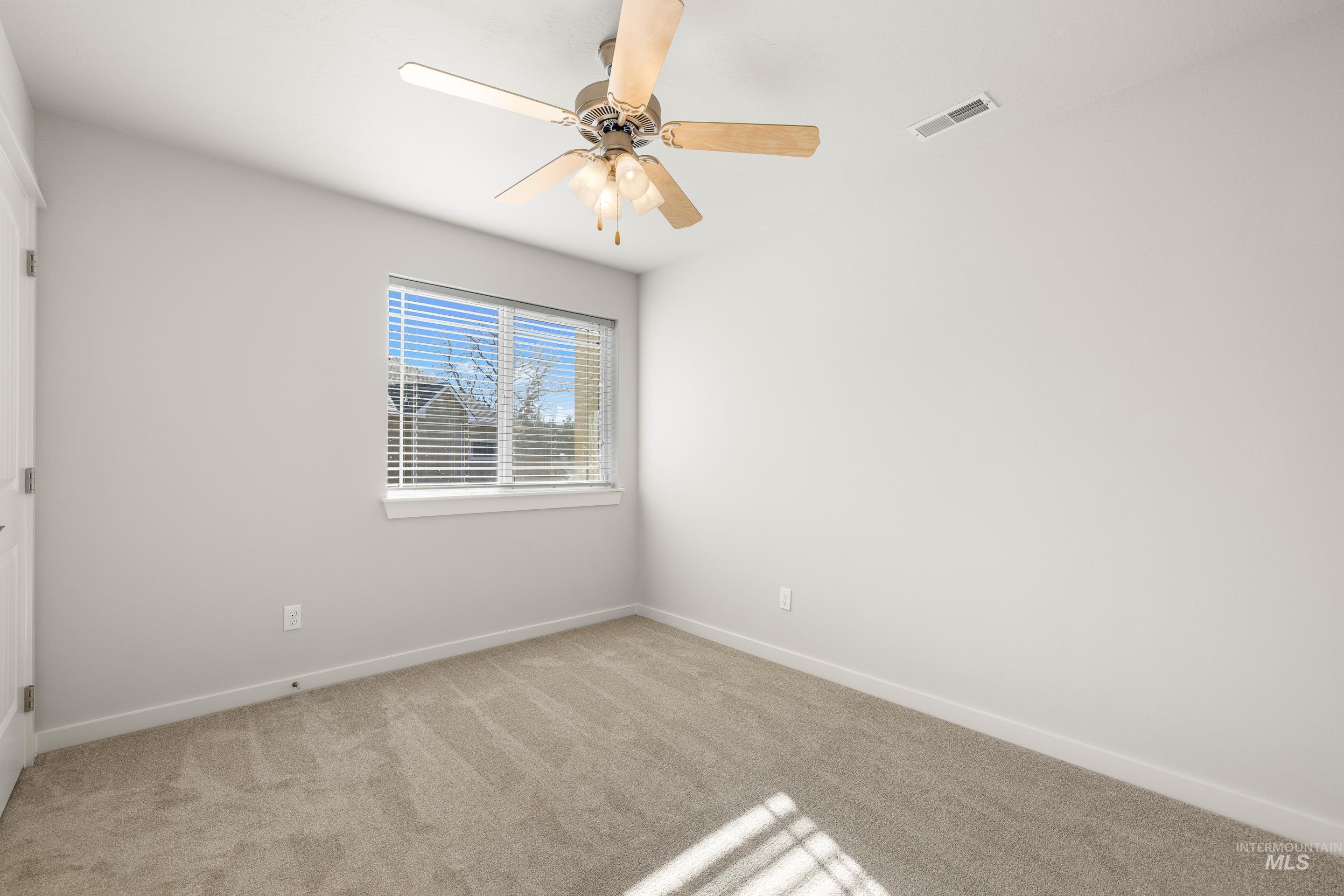 Unfurnished room with light colored carpet and a ceiling fan