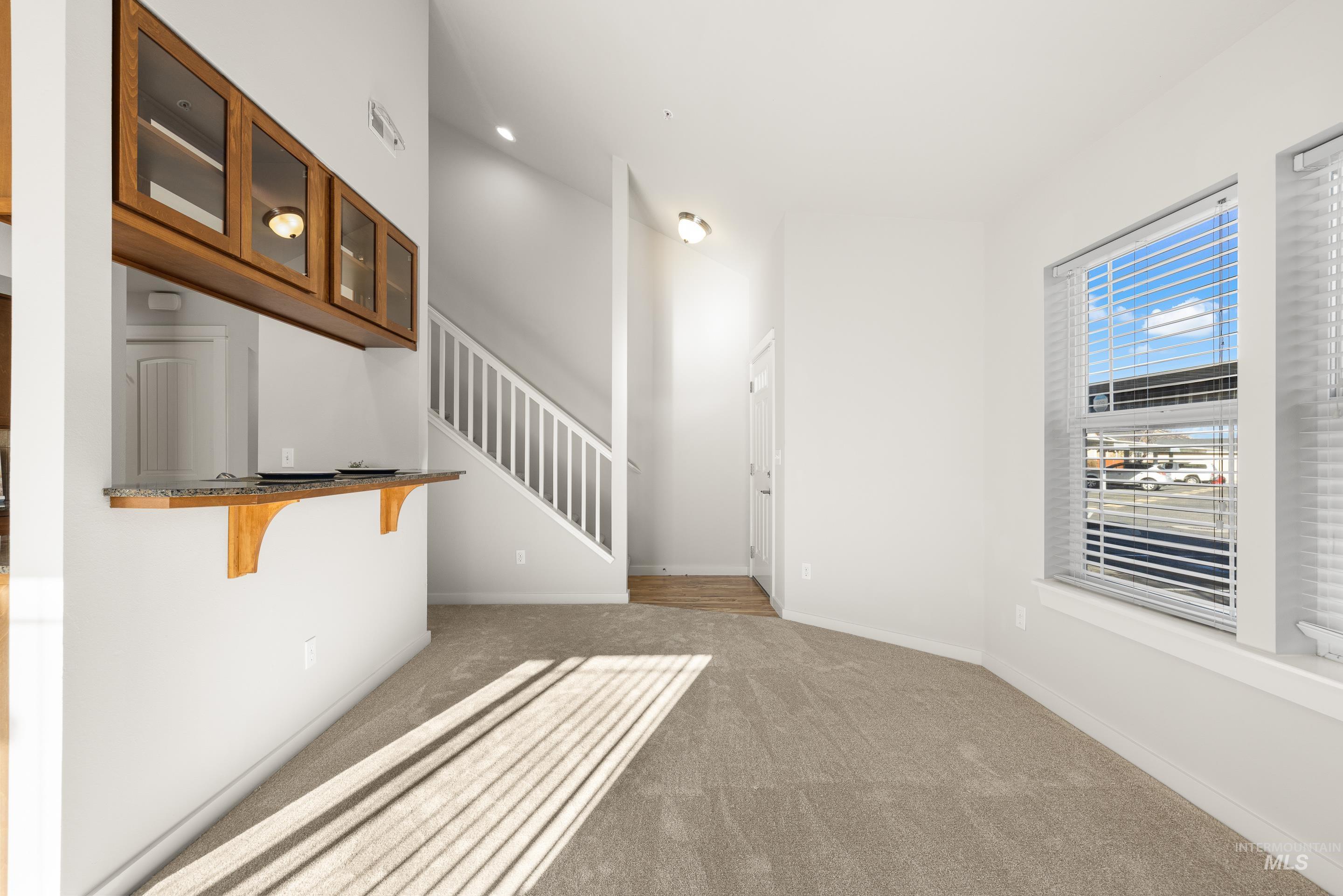 Unfurnished living room featuring stairs and light carpet